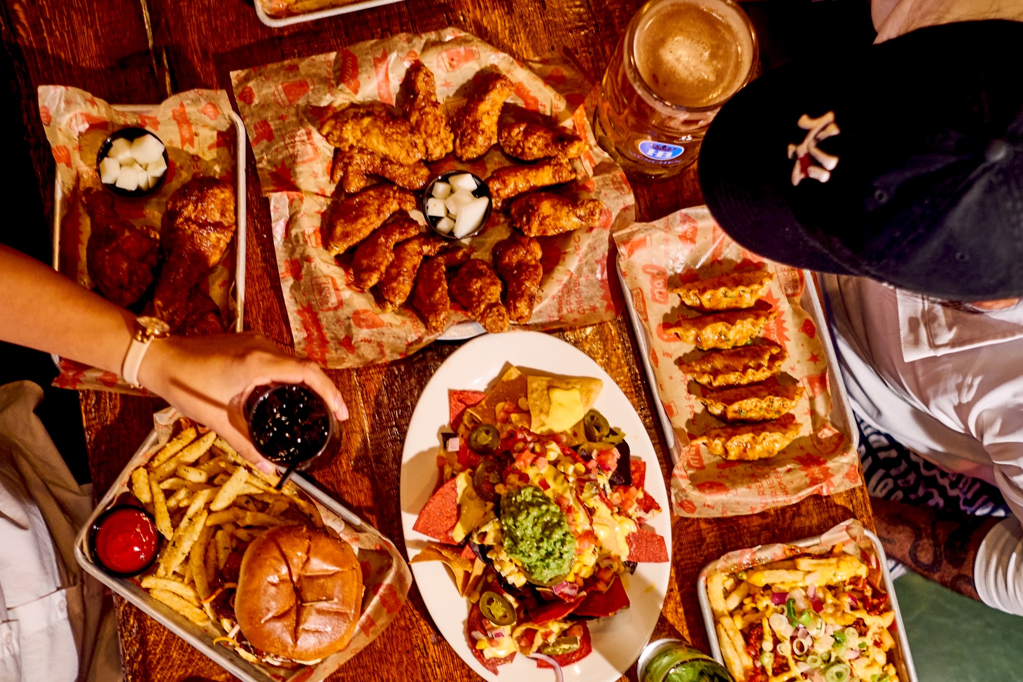 A table spread of wings, fries, burgers and nachos