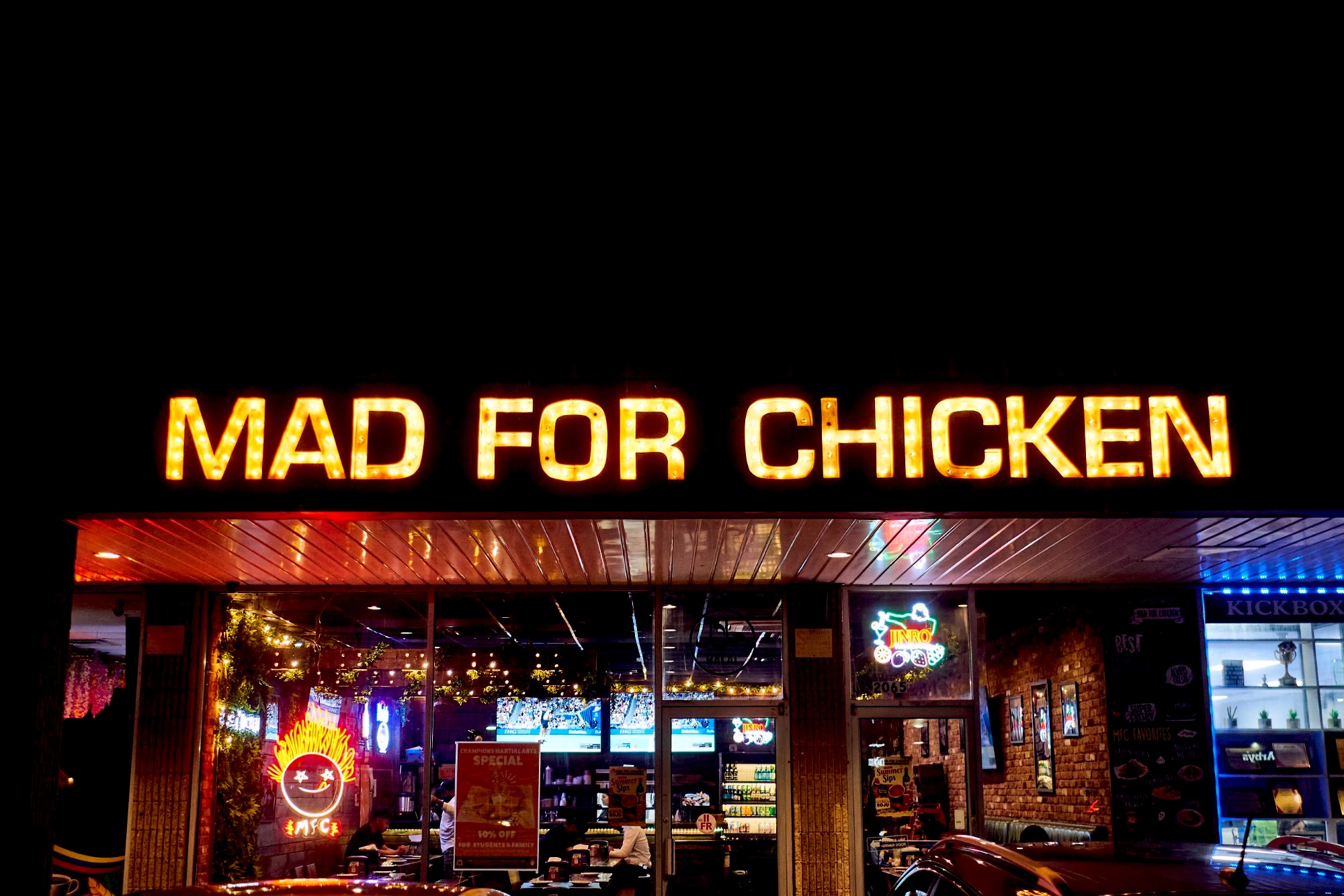 A Mad For Chicken storefront lit up at night